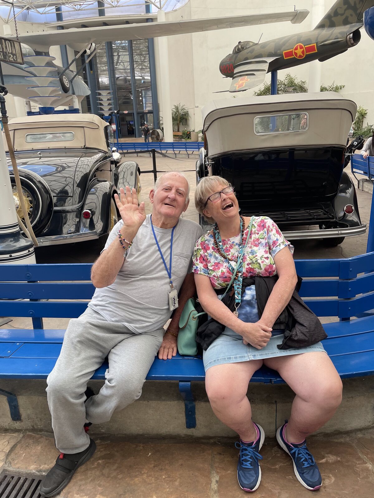 Two ATS participants waving from a bench on a museum visit